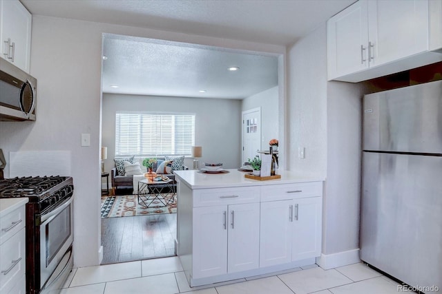 kitchen featuring white cabinets, kitchen peninsula, light tile patterned floors, and stainless steel appliances