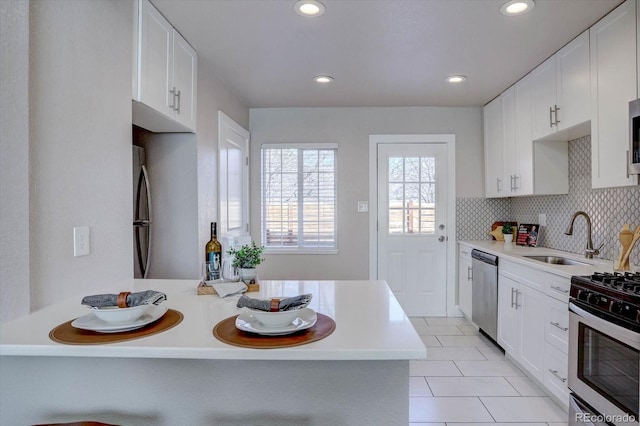 kitchen with light tile patterned floors, white cabinetry, stainless steel appliances, decorative backsplash, and sink