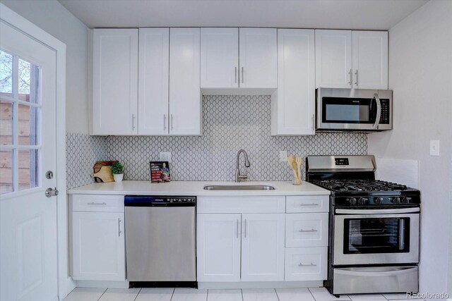 kitchen featuring stainless steel appliances, white cabinetry, tasteful backsplash, and sink