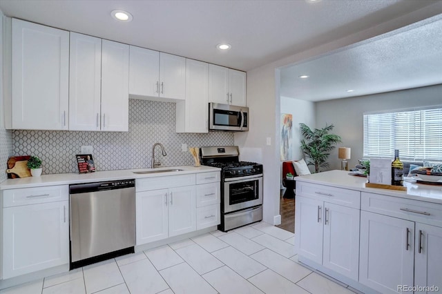 kitchen with backsplash, sink, stainless steel appliances, and white cabinetry