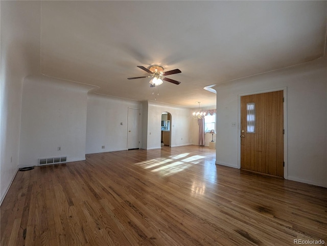 1009 Bush St, Brighton, CO 80601 - unfurnished living room with a ceiling fan, arched walkways, a chandelier, wood finished floors, and baseboards