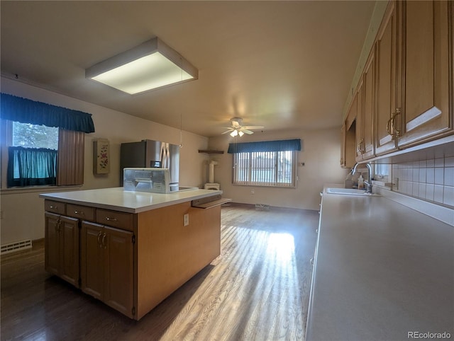 1009 Bush St, Brighton, CO 80601 - kitchen with dark wood-style floors, a sink, a ceiling fan, decorative backsplash, and light countertops