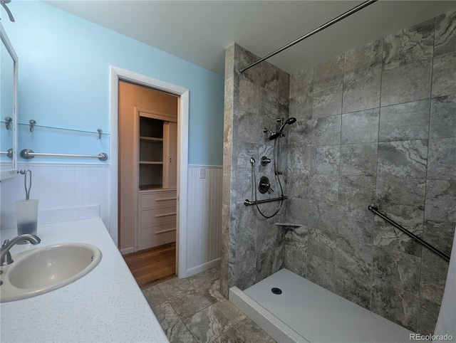 1009 Bush St, Brighton, CO 80601 - bathroom featuring tiled shower, vanity, and wainscoting