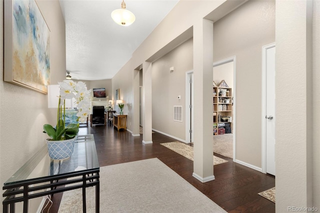 hall featuring decorative columns, a textured ceiling, and dark hardwood / wood-style flooring