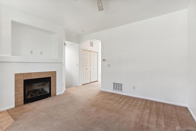 unfurnished living room featuring light carpet, ceiling fan, and a tile fireplace