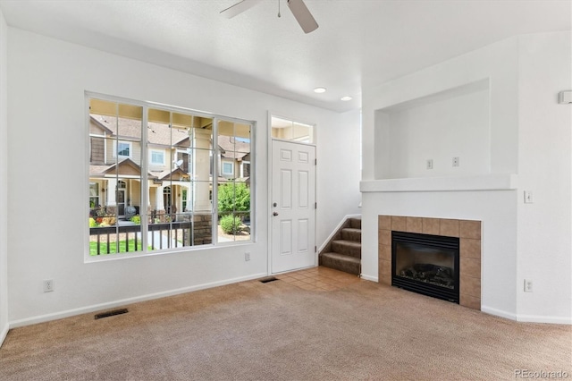 unfurnished living room with a fireplace, light colored carpet, and ceiling fan