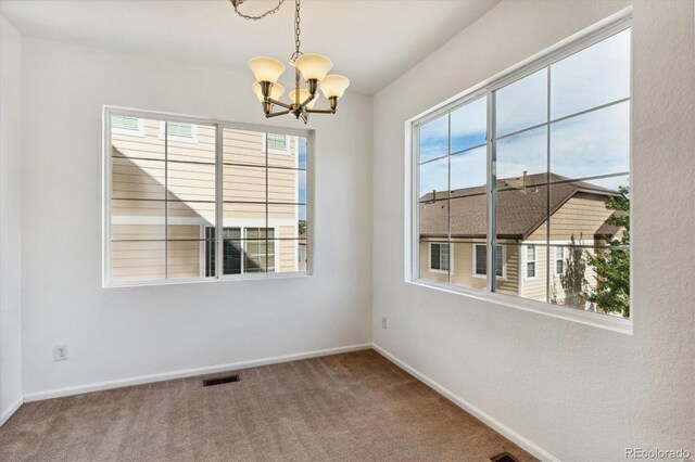 unfurnished room featuring a notable chandelier and carpet floors