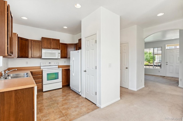 kitchen with white appliances, light colored carpet, and sink