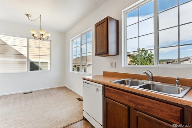 kitchen featuring a healthy amount of sunlight, white dishwasher, sink, and hanging light fixtures