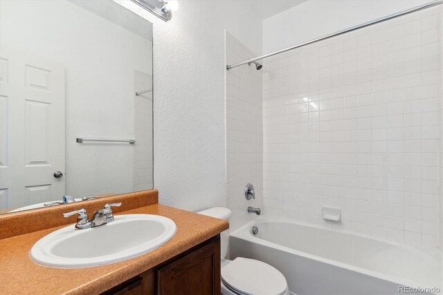 full bathroom featuring tiled shower / bath combo, vanity, and toilet