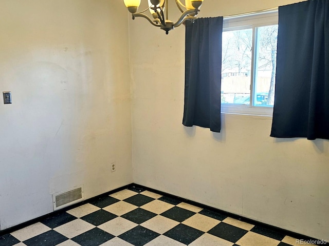 empty room featuring tile patterned floors, a notable chandelier, baseboards, and visible vents