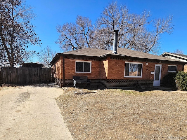 view of front of home with brick siding, roof with shingles, and fence