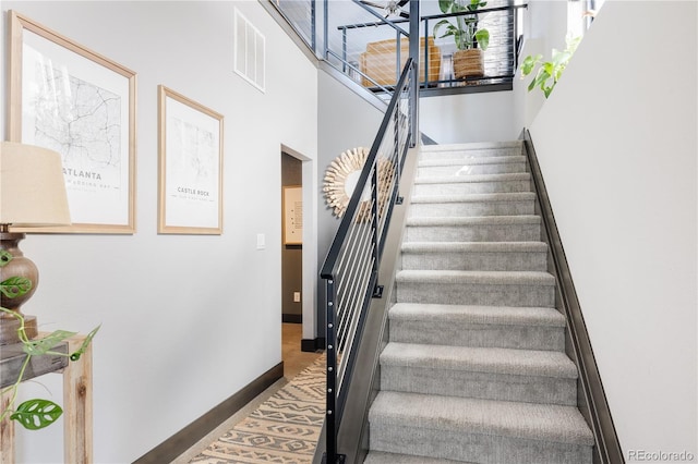 stairway with baseboards and visible vents