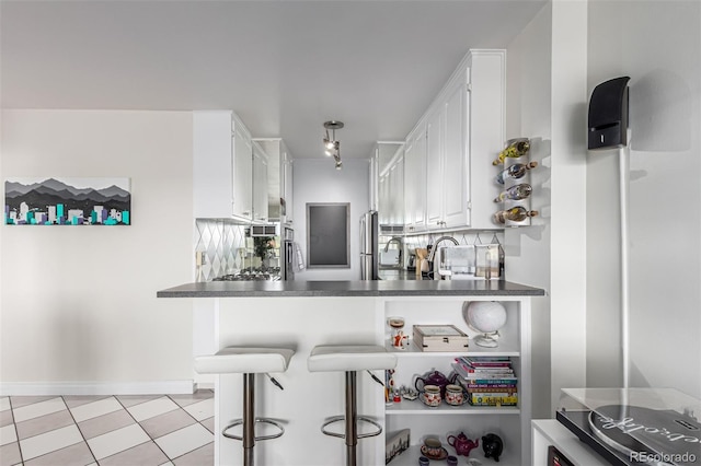 800 N Washington St Unit 804, Denver, CO 80203 - kitchen with white cabinets, dark countertops, a breakfast bar, a peninsula, and freestanding refrigerator