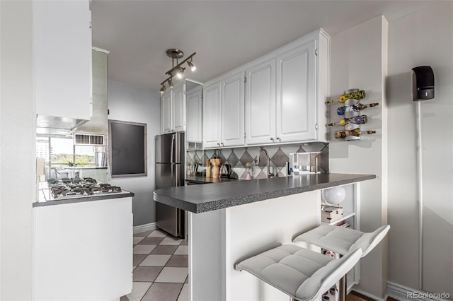 800 N Washington St Unit 804, Denver, CO 80203 - kitchen with appliances with stainless steel finishes, dark countertops, a peninsula, white cabinets, and decorative backsplash