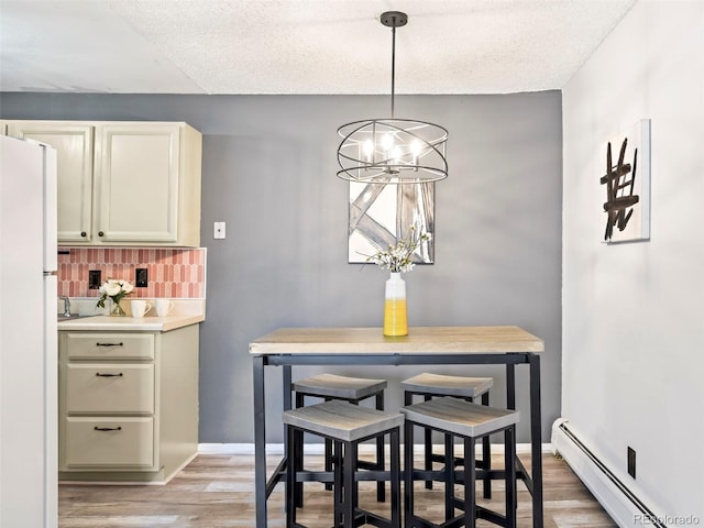 dining space featuring an inviting chandelier, baseboards, light wood-type flooring, and a baseboard radiator