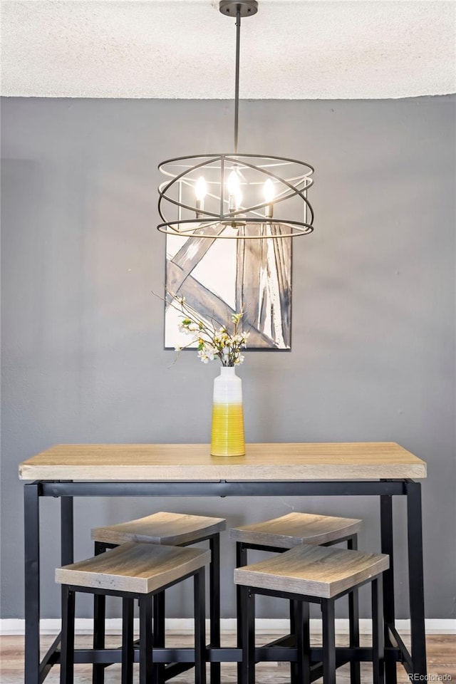 interior details with baseboards, a notable chandelier, wood finished floors, and a textured ceiling