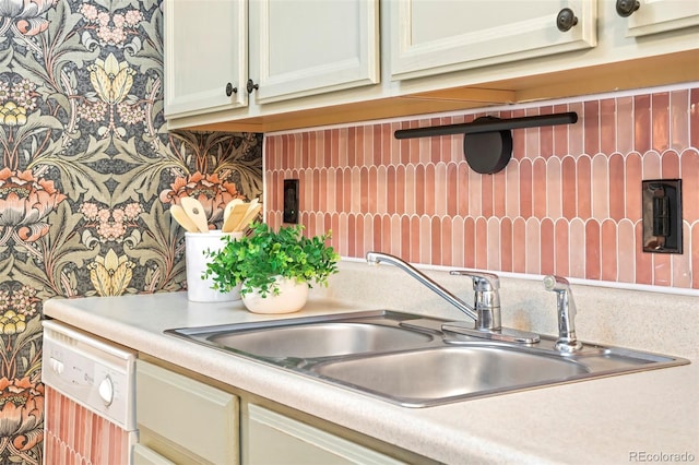 kitchen with dishwasher, light countertops, backsplash, and a sink