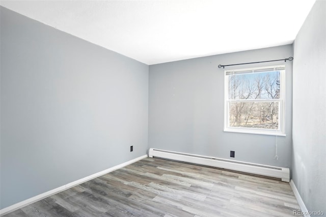 unfurnished room featuring wood finished floors, baseboards, and a baseboard radiator