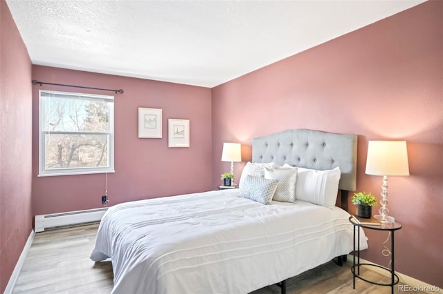 bedroom featuring wood finished floors, baseboards, and baseboard heating