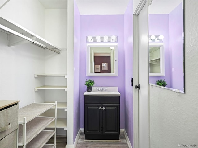 bathroom with vanity, wood finished floors, and baseboards