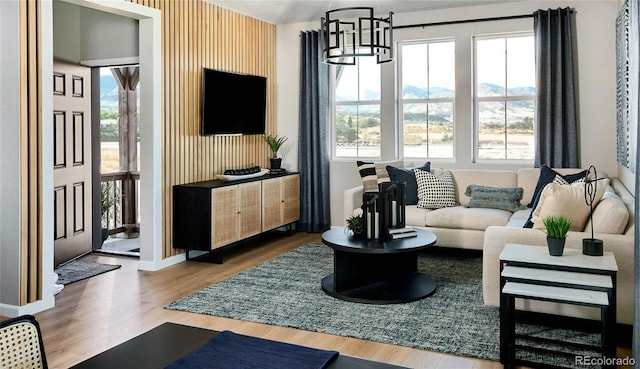 living area with an inviting chandelier, wallpapered walls, baseboards, and wood finished floors