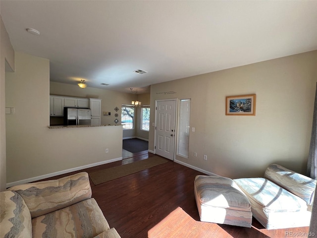 living area with a notable chandelier, baseboards, visible vents, and dark wood-type flooring