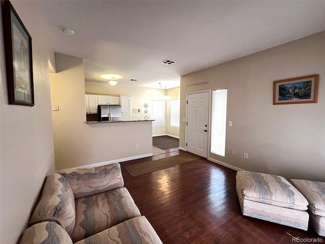 living area with baseboards, visible vents, and dark wood-style flooring