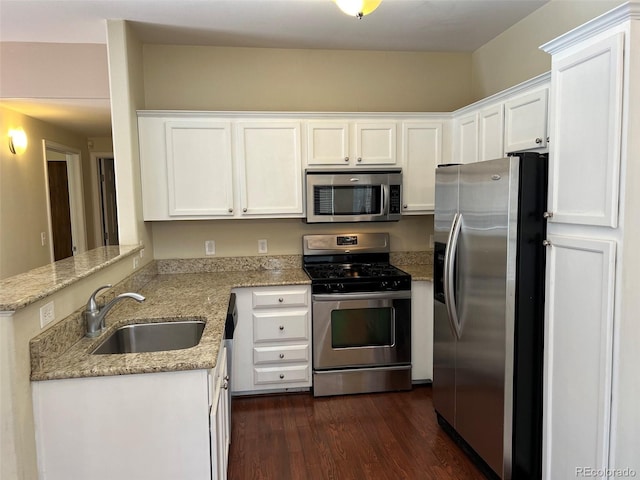 kitchen featuring stainless steel appliances, a sink, white cabinets, light stone countertops, and dark wood-style floors