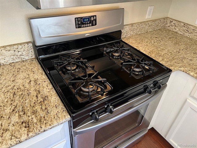 room details with light stone counters, stainless steel range with gas cooktop, and white cabinets