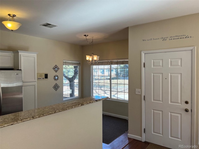 entryway with a chandelier, dark wood finished floors, visible vents, and baseboards