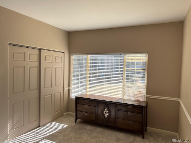 bedroom featuring light carpet, baseboards, and a closet