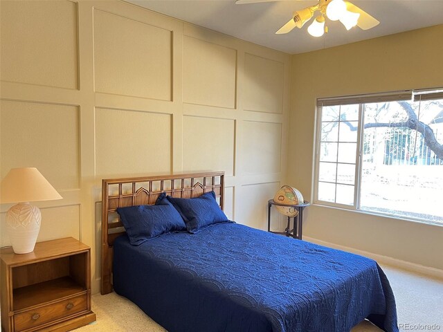 carpeted bedroom with ceiling fan and a decorative wall