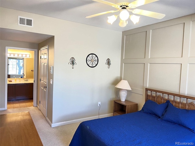 bedroom with baseboards, visible vents, connected bathroom, light colored carpet, and ceiling fan