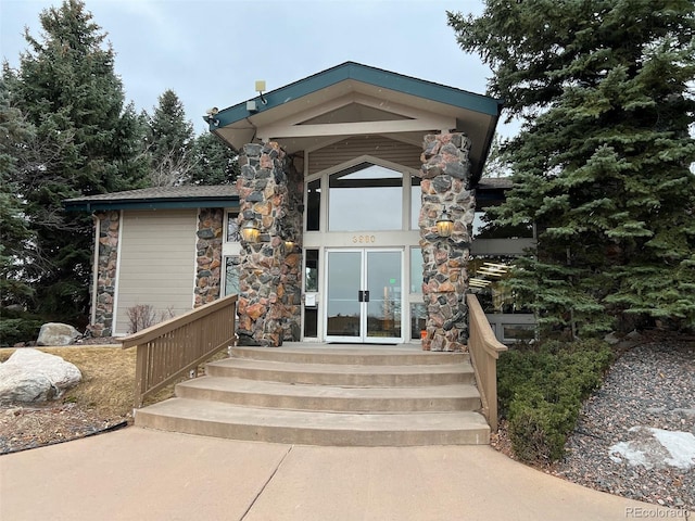 property entrance featuring stone siding and french doors