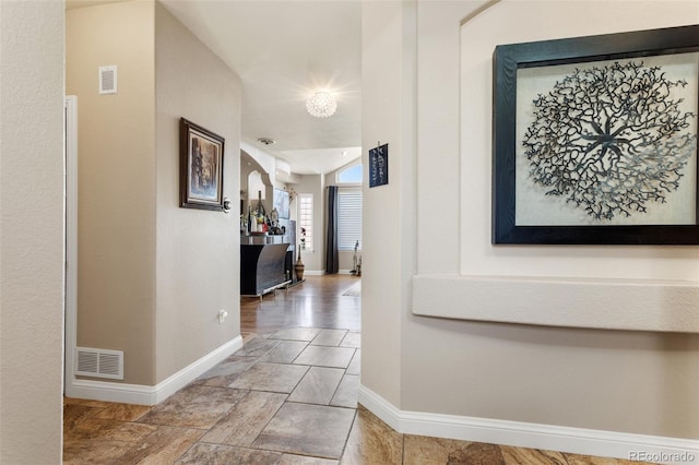 hall featuring visible vents and baseboards