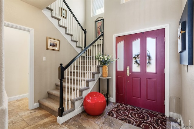 entrance foyer featuring a towering ceiling and baseboards