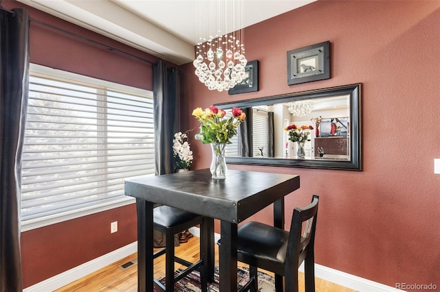 dining room featuring a healthy amount of sunlight, a notable chandelier, baseboards, and wood finished floors