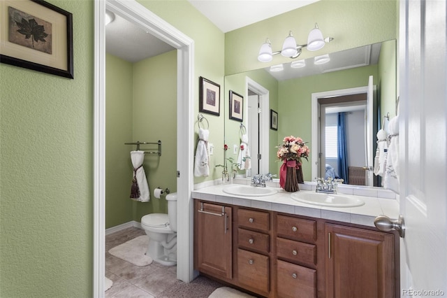 full bathroom with toilet, double vanity, a sink, and ensuite bathroom