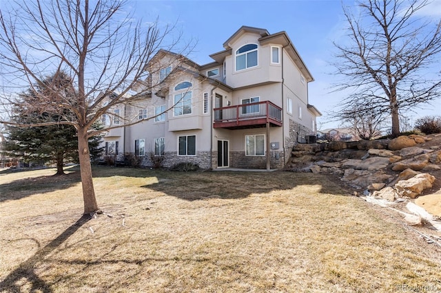 back of property featuring stone siding, a yard, and stucco siding