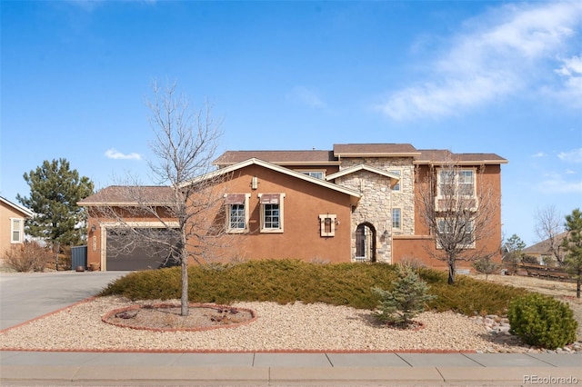 view of front of property featuring driveway, stone siding, an attached garage, and stucco siding