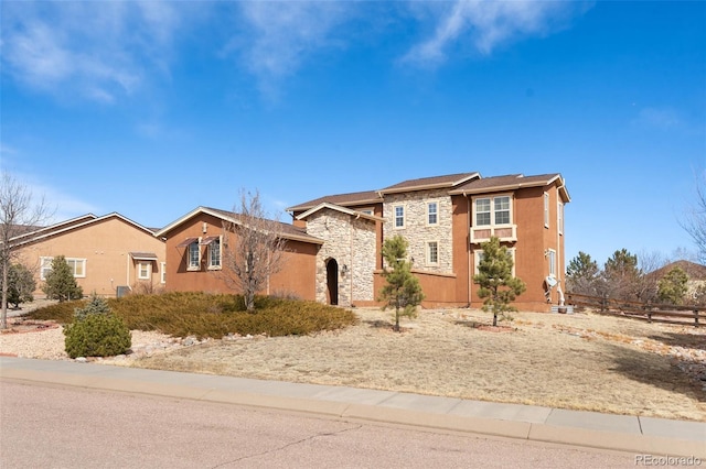 view of front of house with stone siding and fence