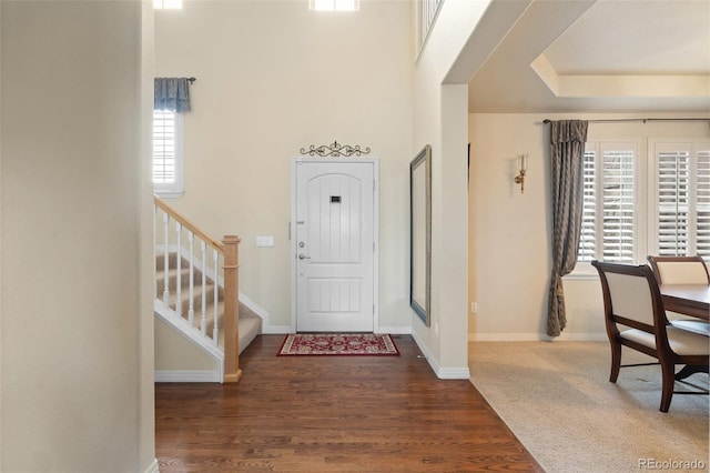 entryway with baseboards, a high ceiling, stairway, and wood finished floors