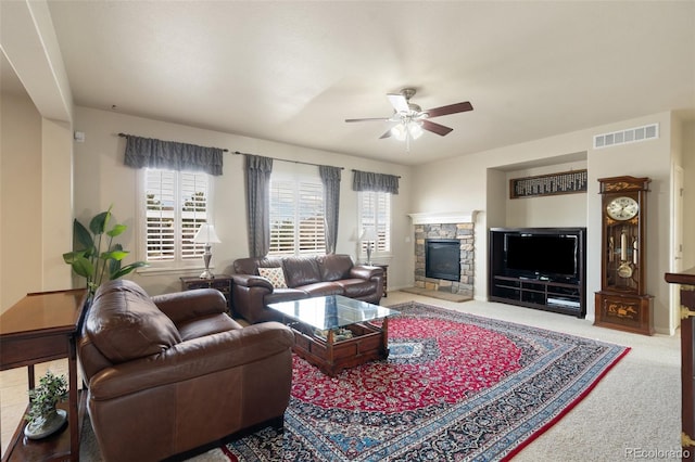 carpeted living room with ceiling fan, a fireplace, and visible vents