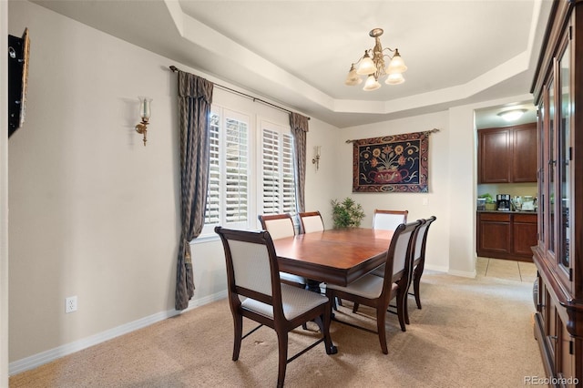 dining space with a notable chandelier, a tray ceiling, baseboards, and light colored carpet