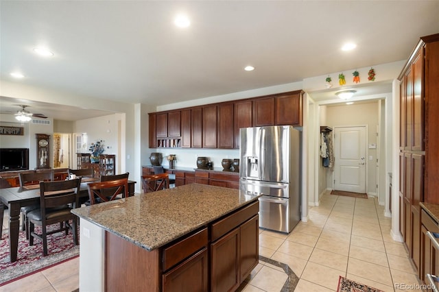 kitchen with light tile patterned floors, light stone counters, recessed lighting, a kitchen island, and stainless steel refrigerator with ice dispenser