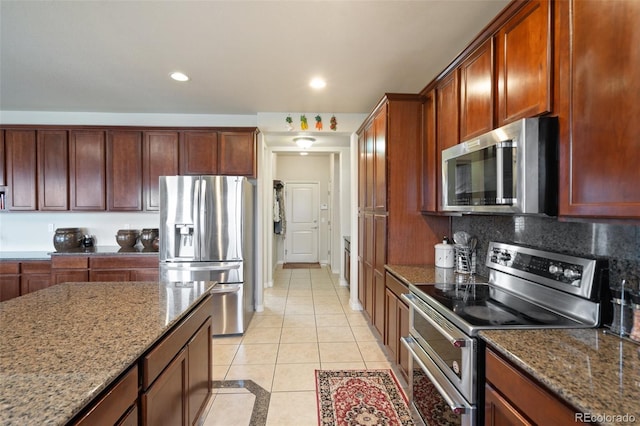 kitchen with appliances with stainless steel finishes, stone countertops, backsplash, and light tile patterned floors