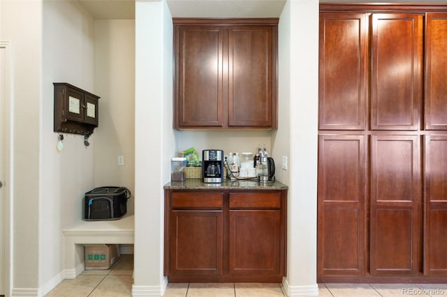 bar with a dry bar, light tile patterned floors, and baseboards