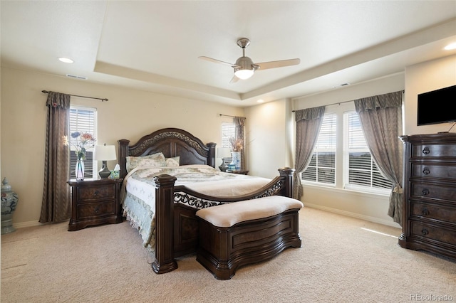 bedroom with visible vents, a tray ceiling, and light colored carpet