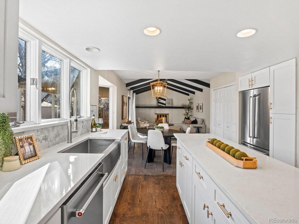 kitchen featuring sink, dark wood-type flooring, stainless steel appliances, vaulted ceiling, and white cabinets